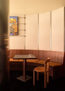 Warm and inviting dining space with wooden walls and floors, featuring a small table and chairs, and a nearby bench