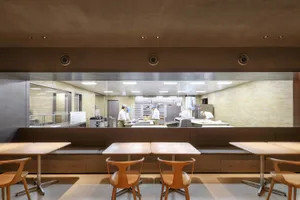 工業風廚房餐廳區，配有木桌、椅子、家電，以及窗戶自然光線