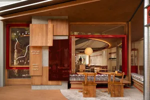 A well-lit restaurant interior with wooden elements, multiple dining tables, and comfortable seating options