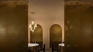 A sophisticated dining area with a large wooden table and chairs, wine glasses, and a warm ambiance