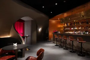 A well-stocked bar area with a long wooden counter and multiple chairs, creating an inviting atmosphere for socializing and enjoying drinks