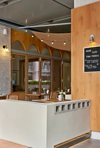 Warm and inviting restaurant interior with wooden tables, chairs, and potted plants, lit by wall lights