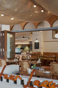 Warm and inviting dining space with wooden tables and chairs, cups on the tables, and a cozy atmosphere