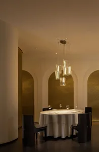 Dining area with a round table, wine glasses, and silverware, surrounded by multiple chairs in a sophisticated setting