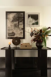 A well-decorated room with a black table, vases, a box, a bowl, and a candle, creating an inviting atmosphere