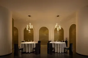 A sophisticated dining area with two long tables, white tablecloths, and neatly arranged chairs, perfect for special events or intimate gatherings