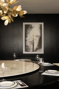 A sophisticated dining area with a large round table, chairs, wine glasses, and a smaller table nearby
