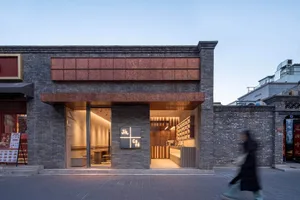 Exterior view of a modern cafe with a brick facade, glass elements, and outdoor seating