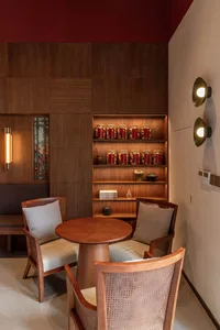 Warm and inviting living space with wooden floors and walls, featuring a dining table and chairs, vases, and a cozy seating arrangement