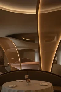 A modern hotel bedroom with a large bed, two chairs, and a comfortable atmosphere, featuring a brown color scheme