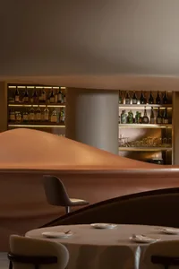 弧形酒吧擺放著酒杯、杯子與碗盤，周圍環繞座椅，營造溫暖親切的氛圍