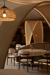 Sophisticated restaurant interior with multiple dining tables, wooden floors, metal accents, and well-designed lighting