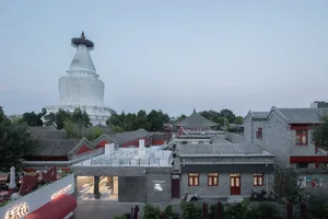 A building with a red roof and white walls, featuring windows on multiple levels, chairs, and a blend of realistic and artistic elements