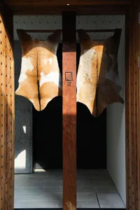 A dimly lit interior space with two large wooden posts adorned with leather animal skins, creating a rustic and unique atmosphere