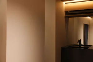A well-lit bathroom stall with a mirror on the wall, reflecting the interior and white walls