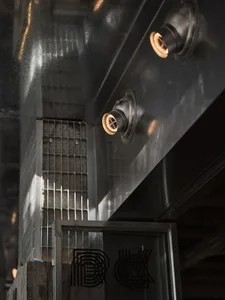 Industrial building with a metal door and window, lit by two overhead lights, suggesting a functional storage or work area