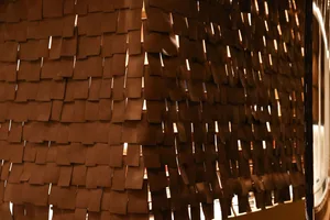 A creative wall covered in paper pieces, illuminated by natural light from a window, with a unique and intricate design