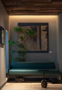 Cozy living area with a couch in front of a wall painting, surrounded by two potted plants and natural light