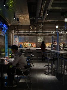A casual bar area with a counter, chairs, and bottles on display, featuring a variety of seating options and a social atmosphere
