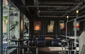 Dimly lit restaurant interior with seating areas, dining tables, and artwork on the walls