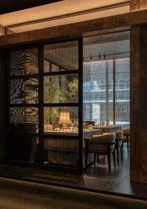 Sophisticated dining area with a large window, chairs, and tableware, illuminated by natural light