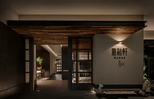 A modern Asian restaurant with a large dining area, potted plants, artwork, and wooden flooring, creating a cozy atmosphere
