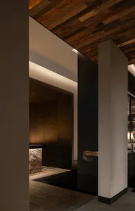 Dining area with wooden walls and floors, featuring a dining table and a kitchenette with a sink, with a warm and inviting atmosphere