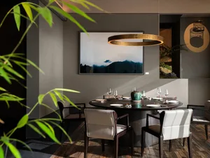 Dining area with a round table, chairs, wine glasses, and a potted plant, creating an inviting and sophisticated atmosphere