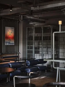 Cozy cafe with brick and metal walls, multiple tables, chairs, and a couch, creating a warm and inviting atmosphere