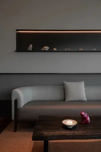 Cozy living room with grey walls, a couch, pillows, a small table, a vase, and a bowl