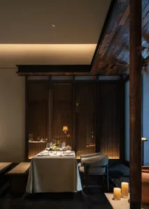 A sophisticated dining area with a table set for a meal, featuring fine dinnerware, wine glasses, and decorative items
