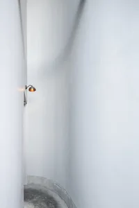 A minimalist white wall with two lights mounted on it, in a possibly empty hallway or small space