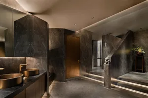 Luxurious bathroom with marble floors and walls, featuring two sinks and a staircase