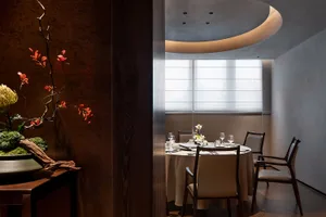 A formal dining area with a round table set with various items, surrounded by chairs with and without backs, creating a sophisticated atmosphere