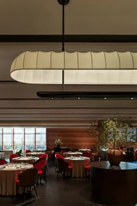 Modern restaurant interior with wooden elements, red and white accents, and potted plants, creating a warm and inviting atmosphere