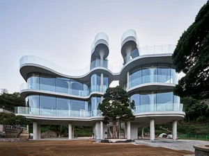 A modern building with a tree-like design, featuring glass walls and a clear glass ceiling, set against a neutral background