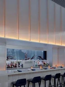 A modern bar with a stainless steel counter, comfortable seating, and warm lighting creating a cozy atmosphere