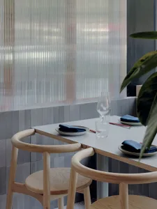 A formal dining area with a white table surrounded by chairs and various table settings, in a restaurant or upscale home setting