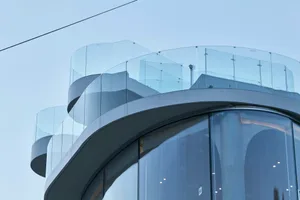 A modern building interior with a glass staircase wall, two sets of stairs, and a sleek design