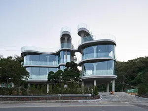 Two modern glass and steel buildings connected by a bridge, with multiple windows allowing natural light to enter the spaces
