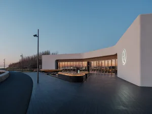 A modern restaurant interior with a curved design, featuring dining tables and chairs in a stylish environment