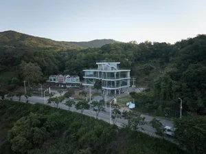 A contemporary building with a concrete exterior, surrounded by trees, featuring a mix of modern and traditional elements, with clean lines and minimalistic design