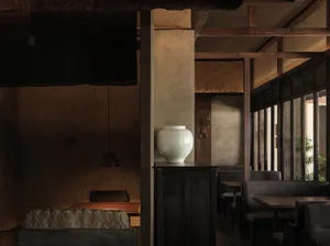 Cozy Asian restaurant interior with wooden walls and floors, featuring chairs, dining tables, and a vase, creating a warm and inviting atmosphere