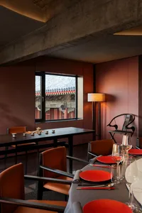 A well-organized dining area with a large wooden table, multiple chairs, wine glasses, and vases, creating a cozy and elegant atmosphere for social gatherings