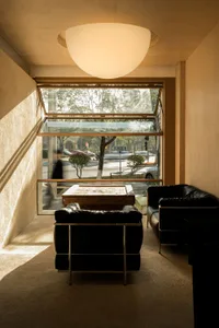 Comfortable living space with a black leather couch, two chairs, and natural light from a large window