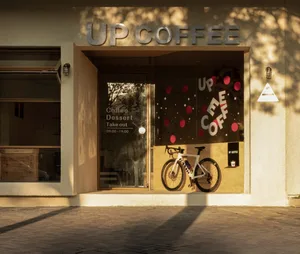 A cozy coffee shop interior with a dining table, chairs, and bicycles outside the entrance