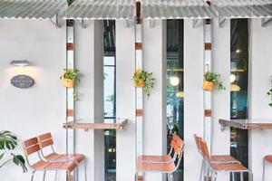 Two dining tables with four chairs and potted plants as centerpieces in a warm and inviting restaurant space