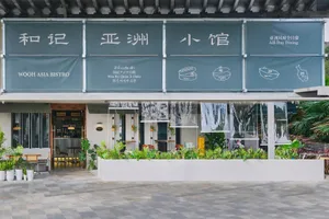 一家溫馨的亞洲餐廳，設有大型招牌、盆栽、椅子與餐桌，為顧客營造舒適氛圍
