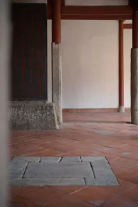 A serene indoor space with stone walls adorned with Chinese writing, featuring two pillars and intricate design elements