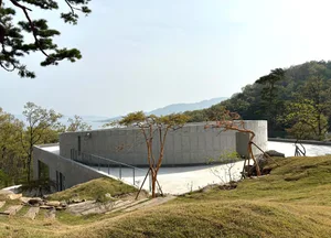 A serene open area with a concrete house surrounded by trees, with a calm atmosphere